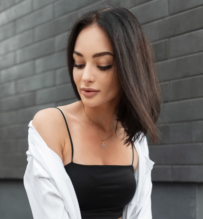 woman outside looking down with jacket hanging off her shoulders