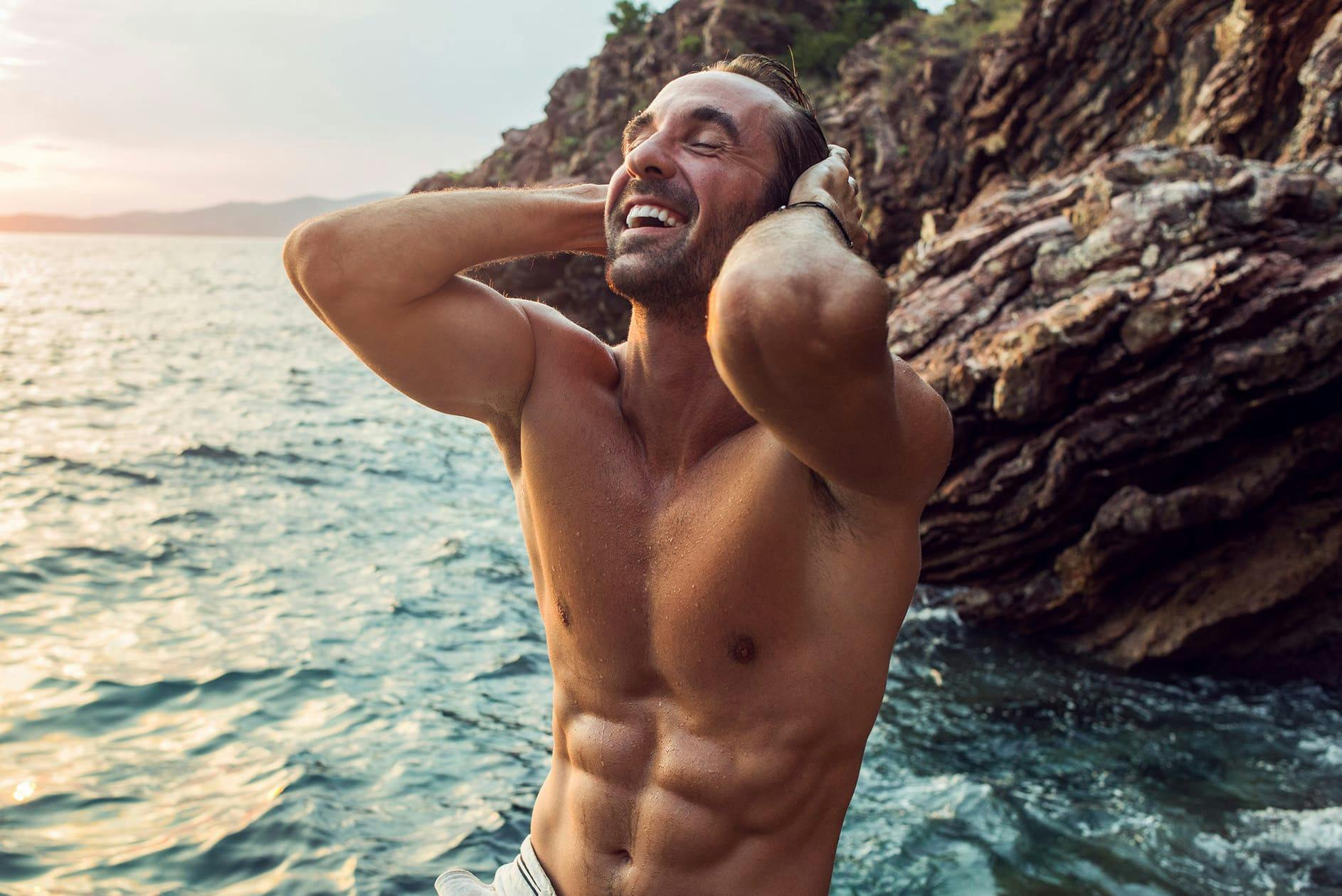 man in the ocean brushing his wet hair back