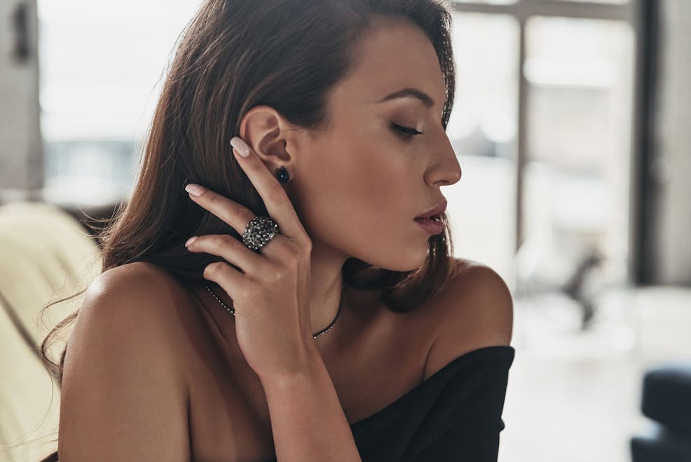 woman's side profile while shes moving her hair to behind her ear