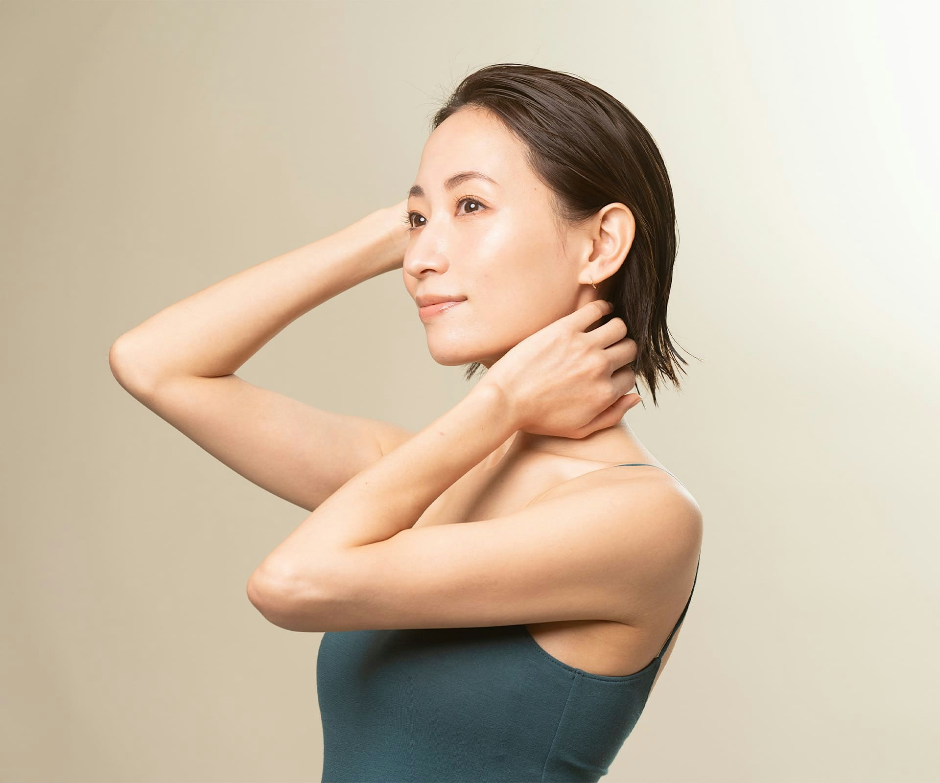 asian woman with short hair touching her head and her neck with her hands