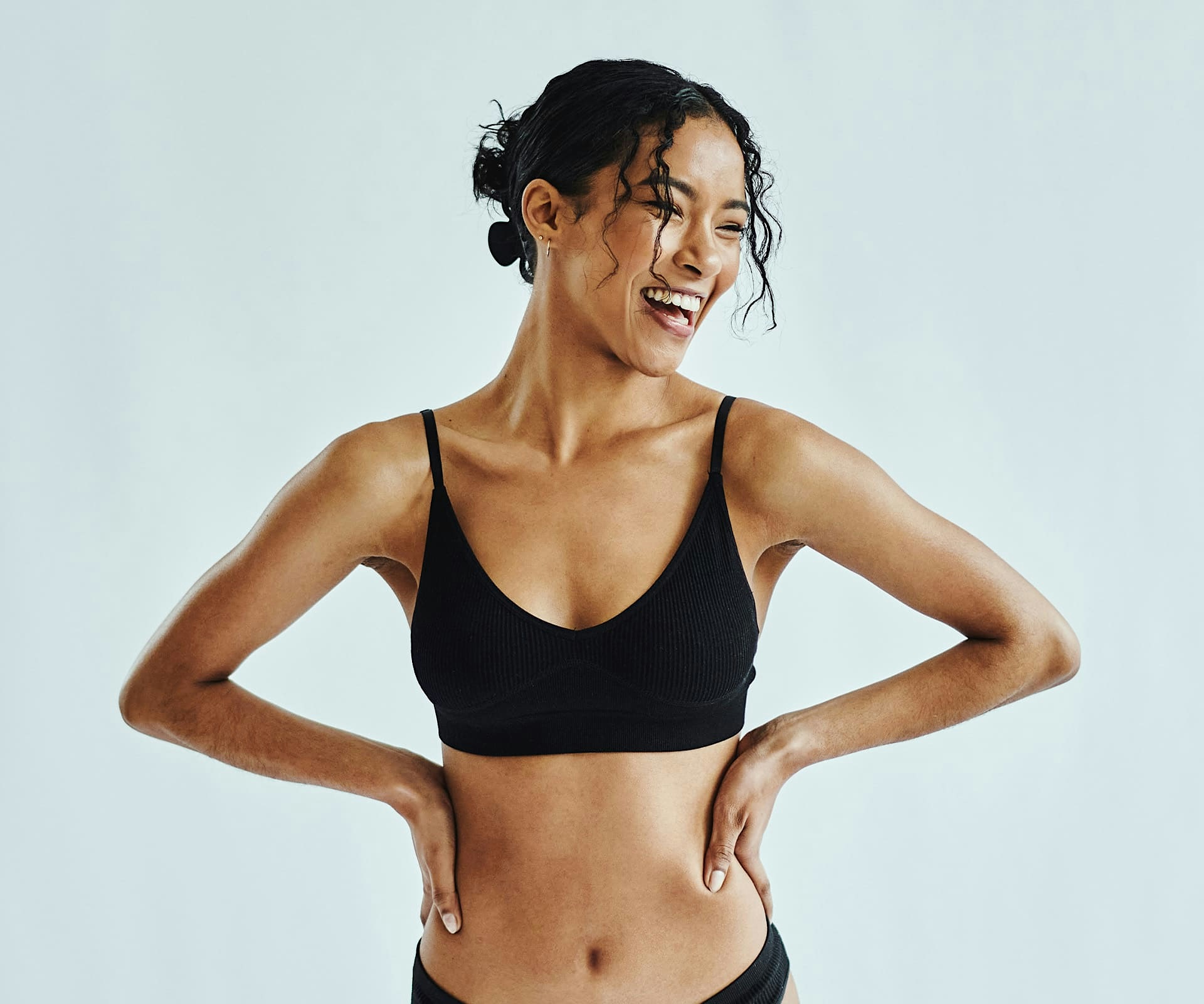 woman in black bodysuit outside sitting and leaning her head back