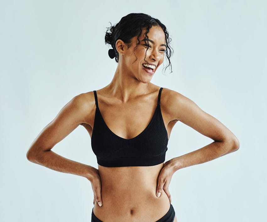 woman in black bodysuit outside sitting and leaning her head back