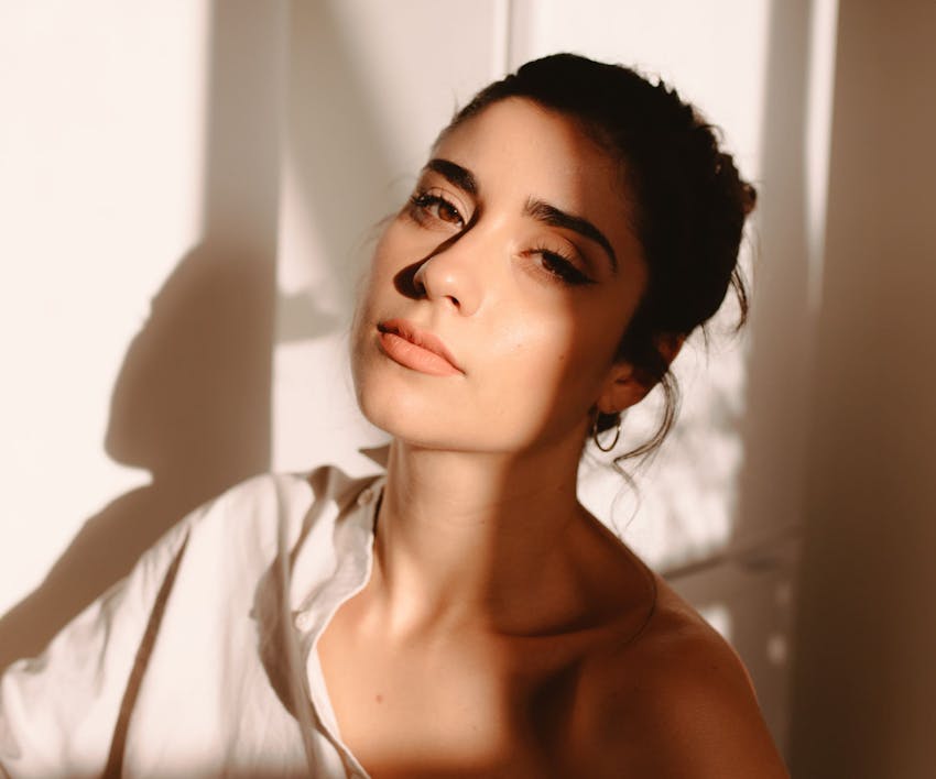 woman sitting with white button up shirt, heavy shadow on the side of her face
