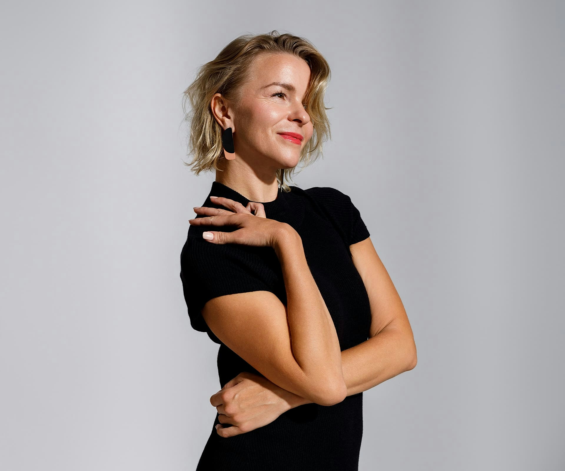 woman with short blonde hair and her hand on her own shoulder