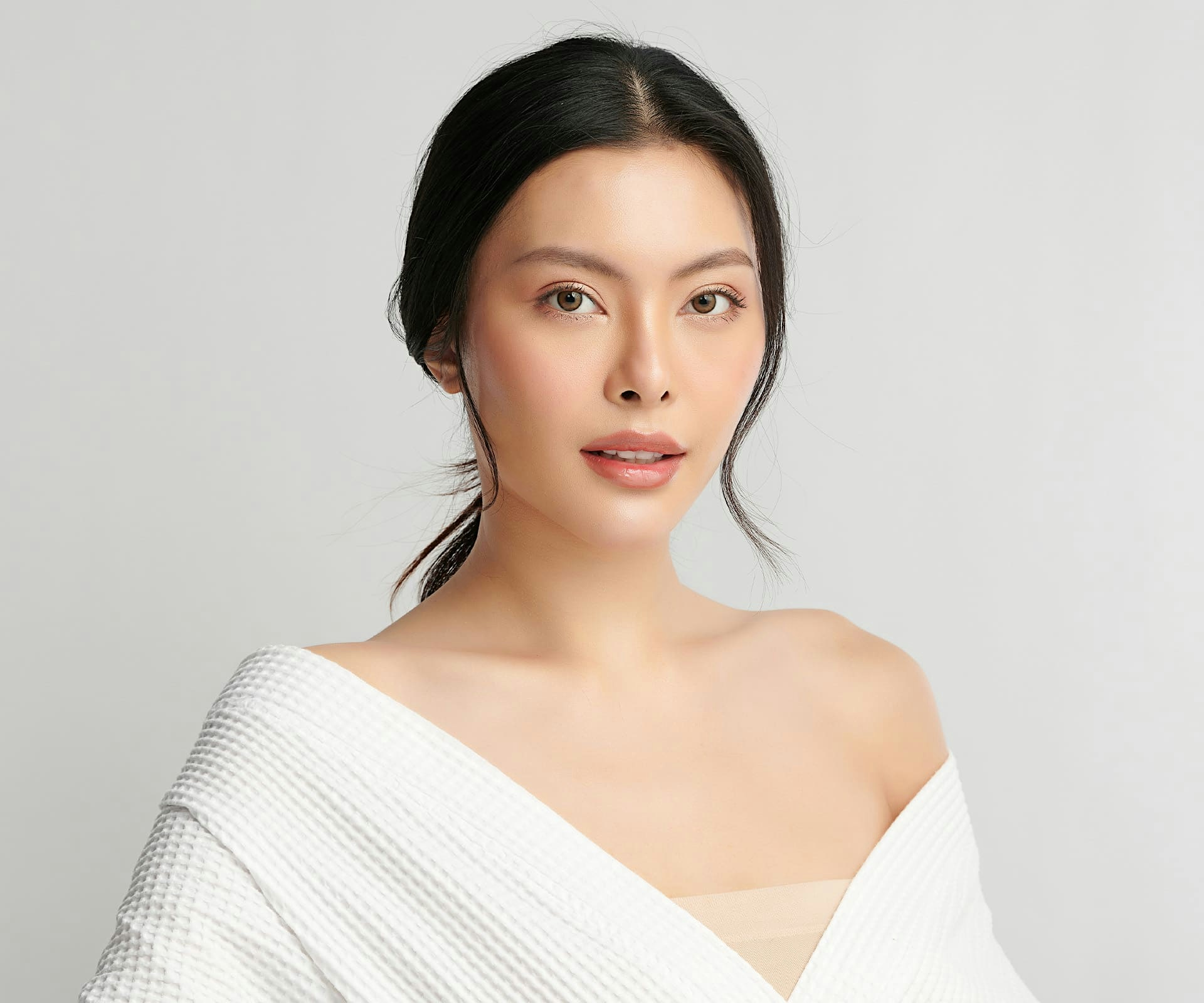 woman with low ponytail in white over-sized top