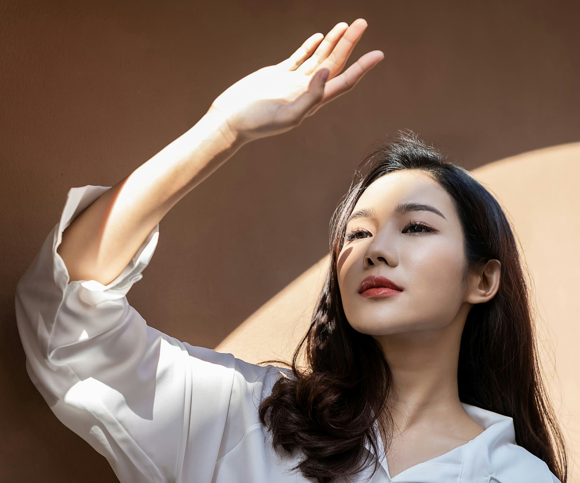 woman standing blocking sunlight from her face with her hand
