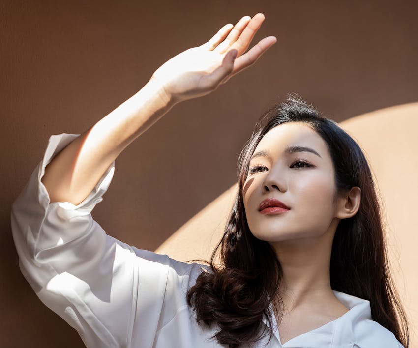 woman standing blocking sunlight from her face with her hand