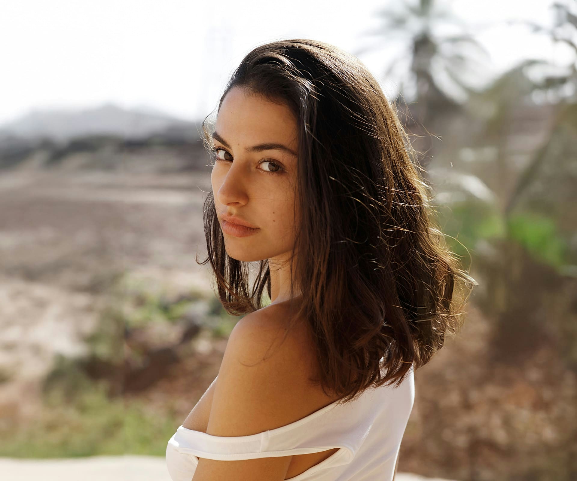 dark haired woman looking back at camera outside