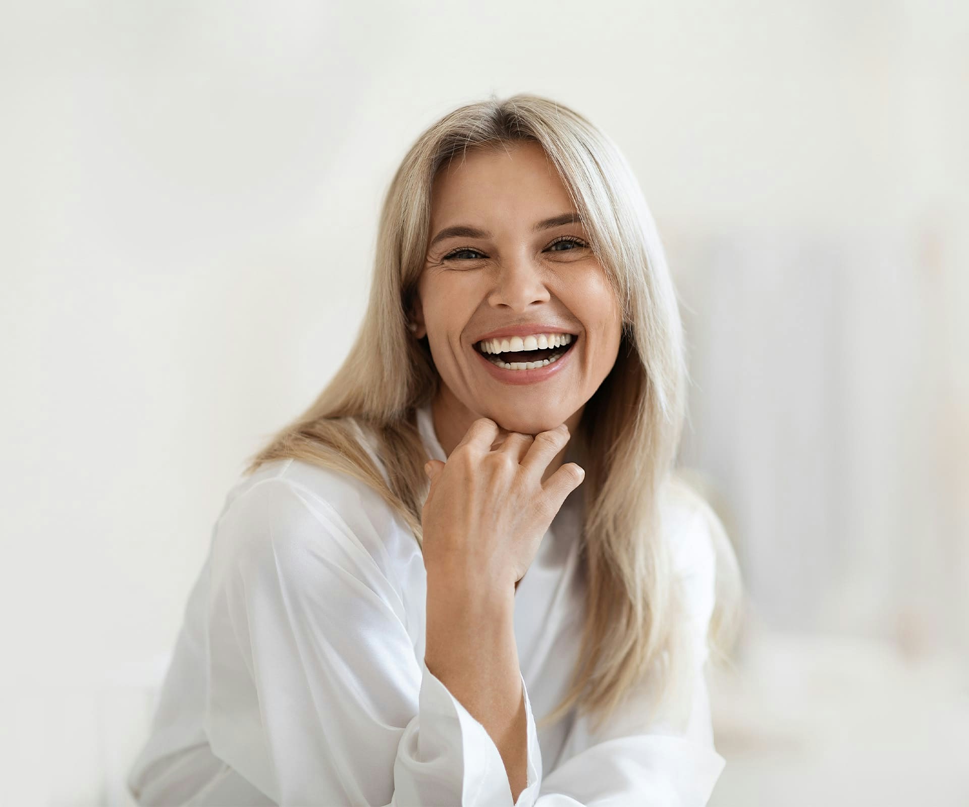 woman laughing while her chin rests on her hand