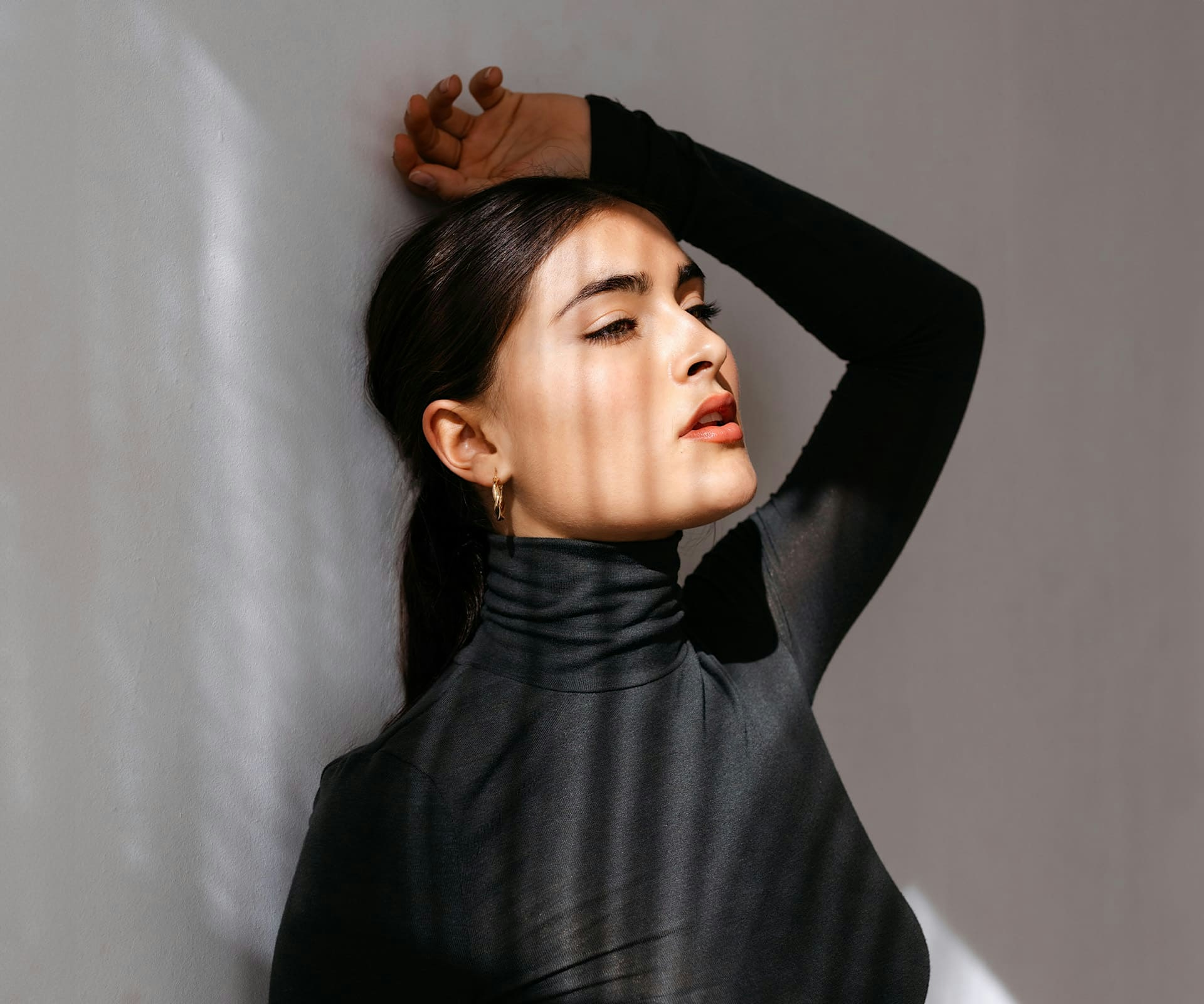 woman in black turtle neck leaning against wall