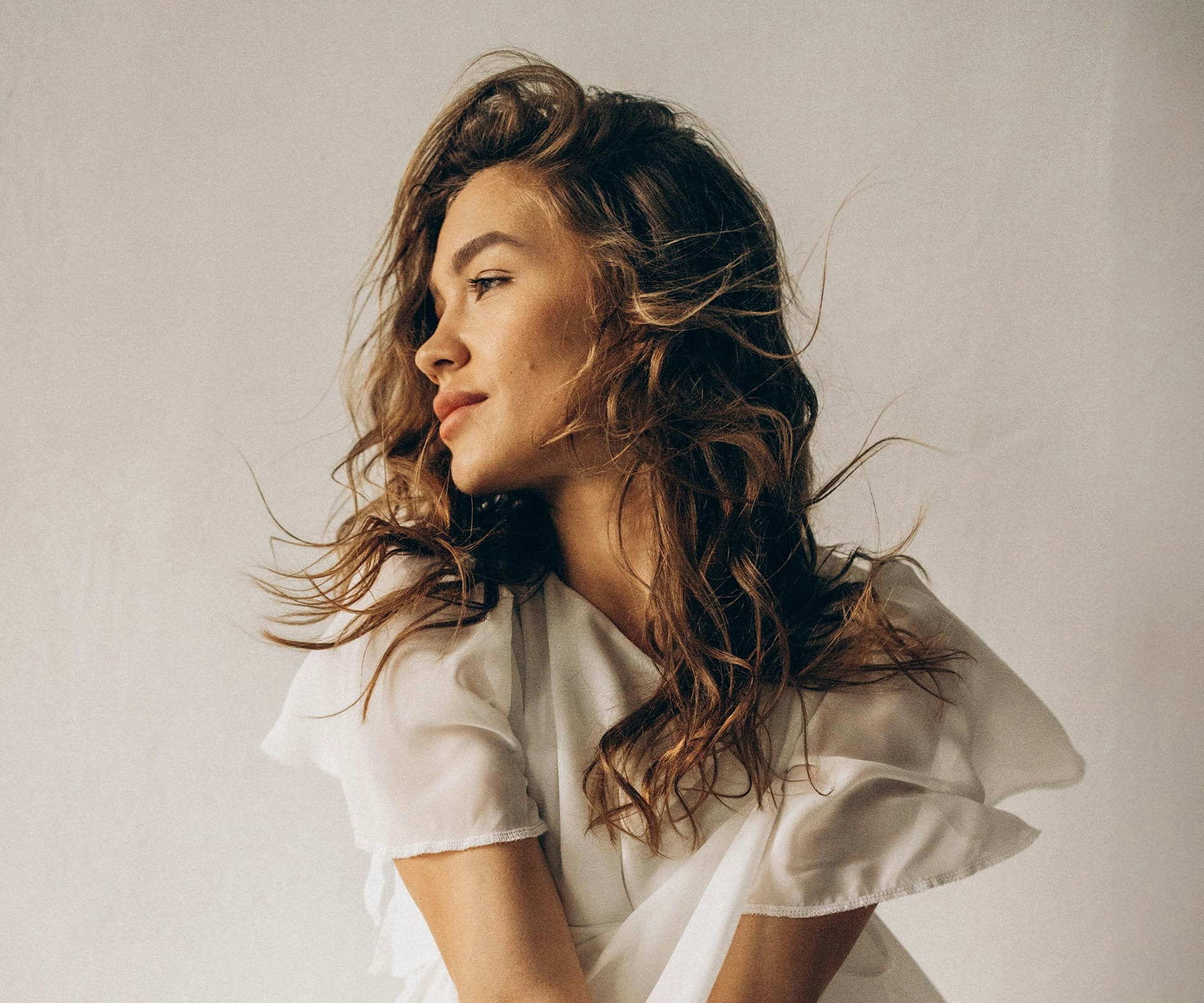 woman in flowing top looking to the side while wind blows
