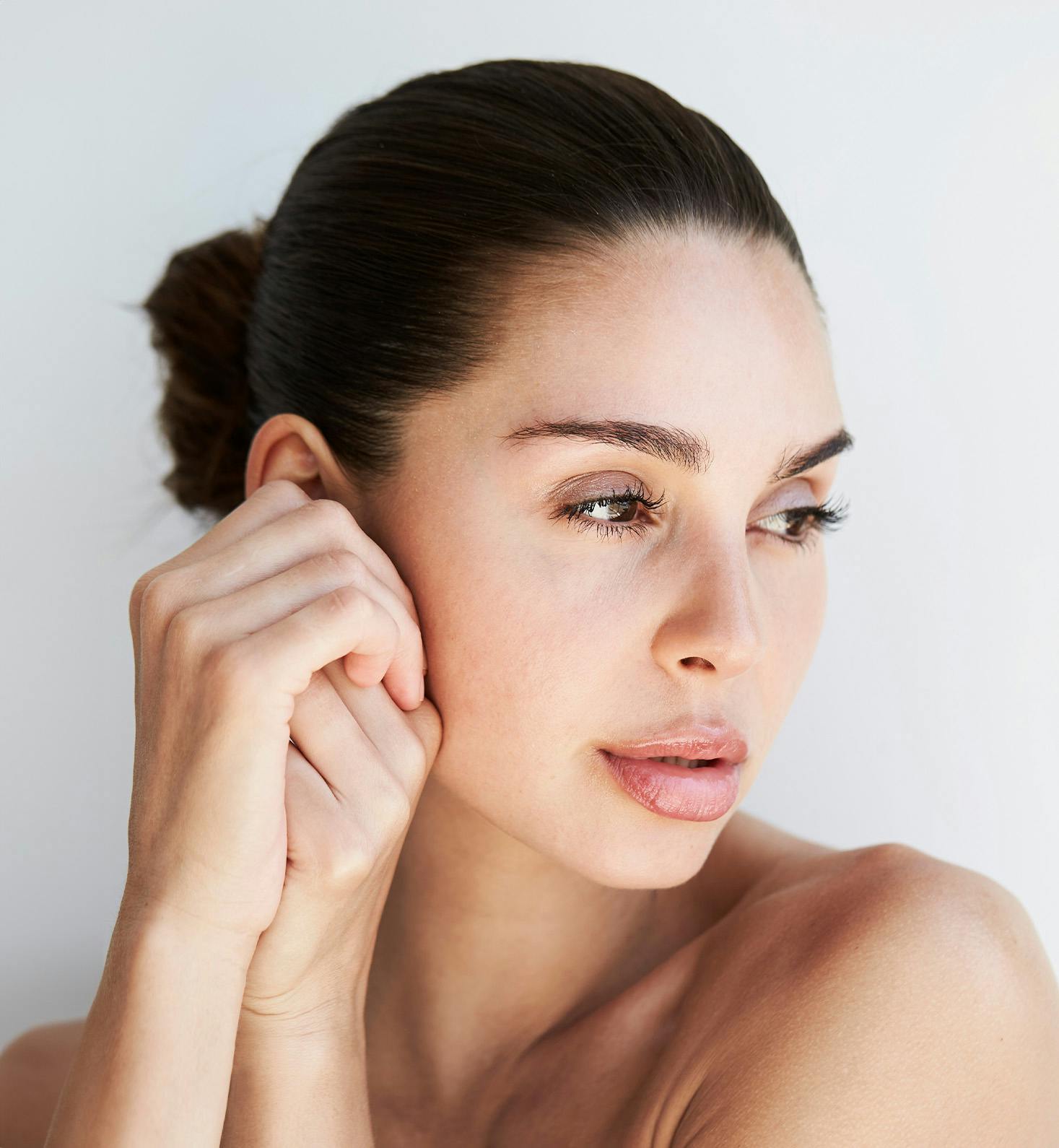 close up on woman's face facing downwards while touching her cheek with her hand
