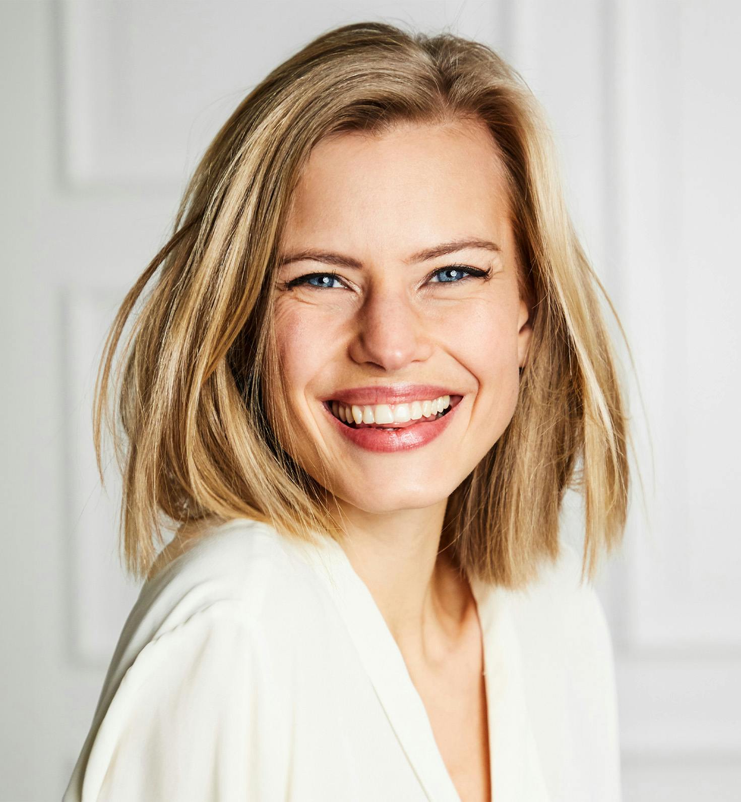 blond woman with bob haircut smiling towards