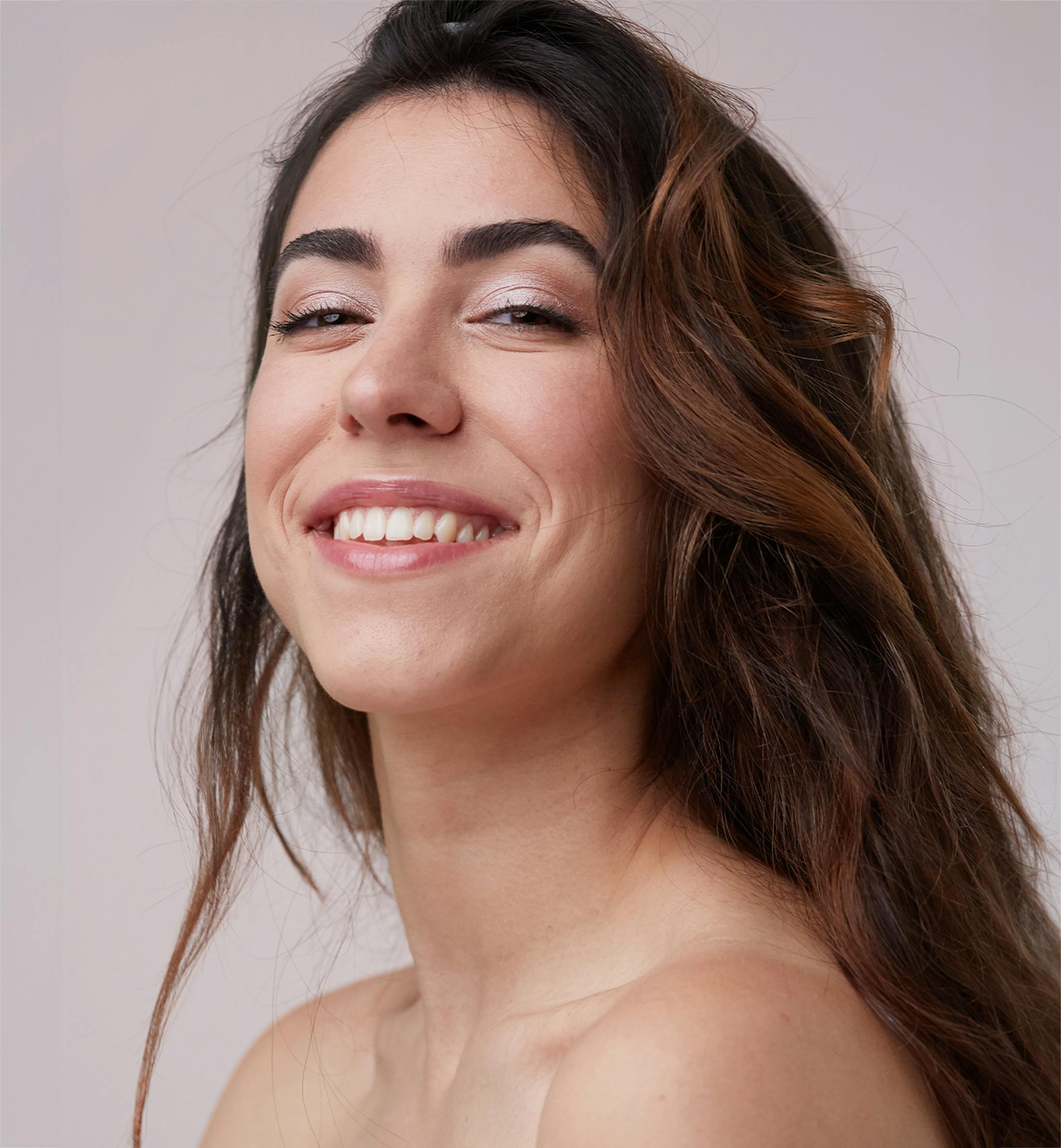 woman smiling forward while lifting her chin up slightly