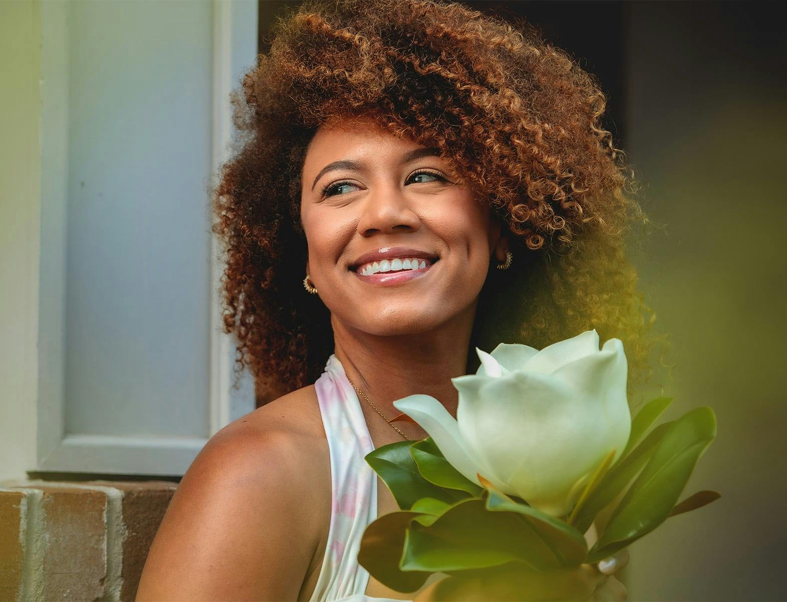 woman with afro holding a big white flower