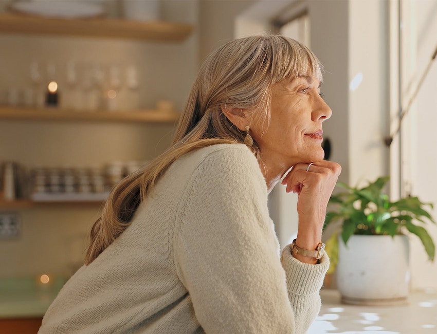 older woman leaning on counter and holding her chin up with her fist