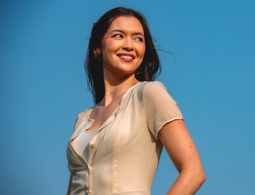 woman smiling while looking to the right with hand on her hip