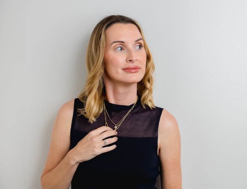 woman looking to the right and touching her necklace