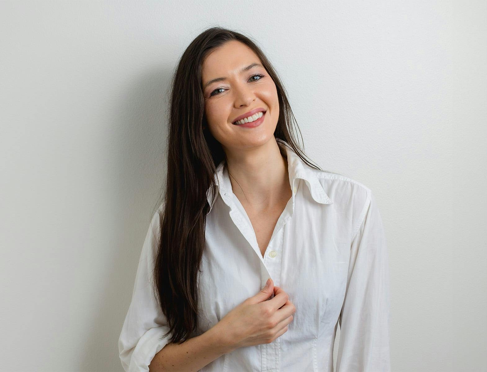 woman smiling and touching the button of her shirt