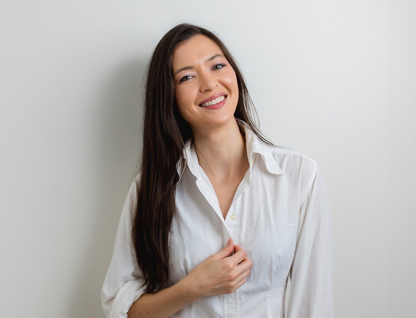 woman smiling and touching the button of her shirt