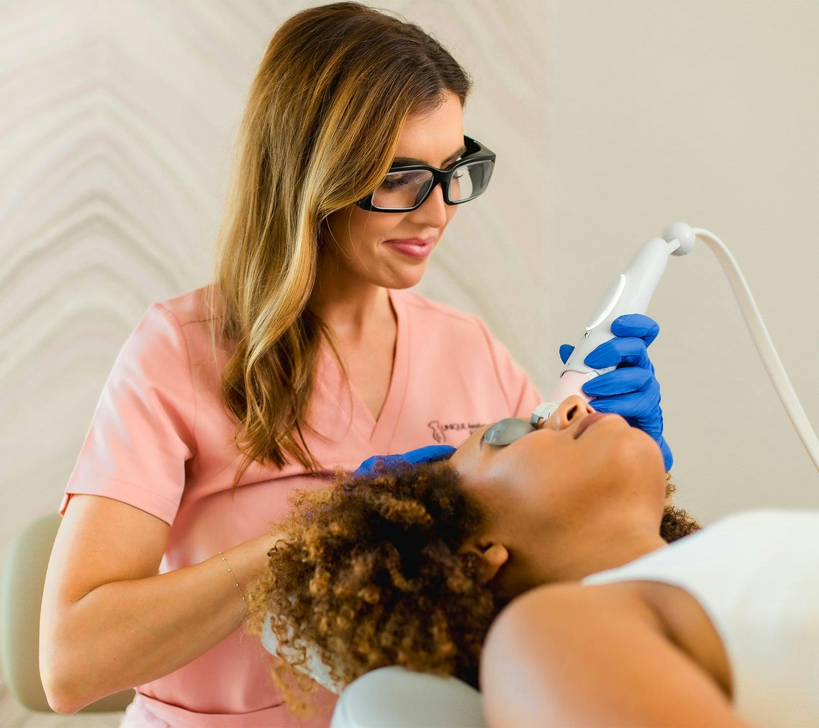 nurse smiling as she does facial treatment