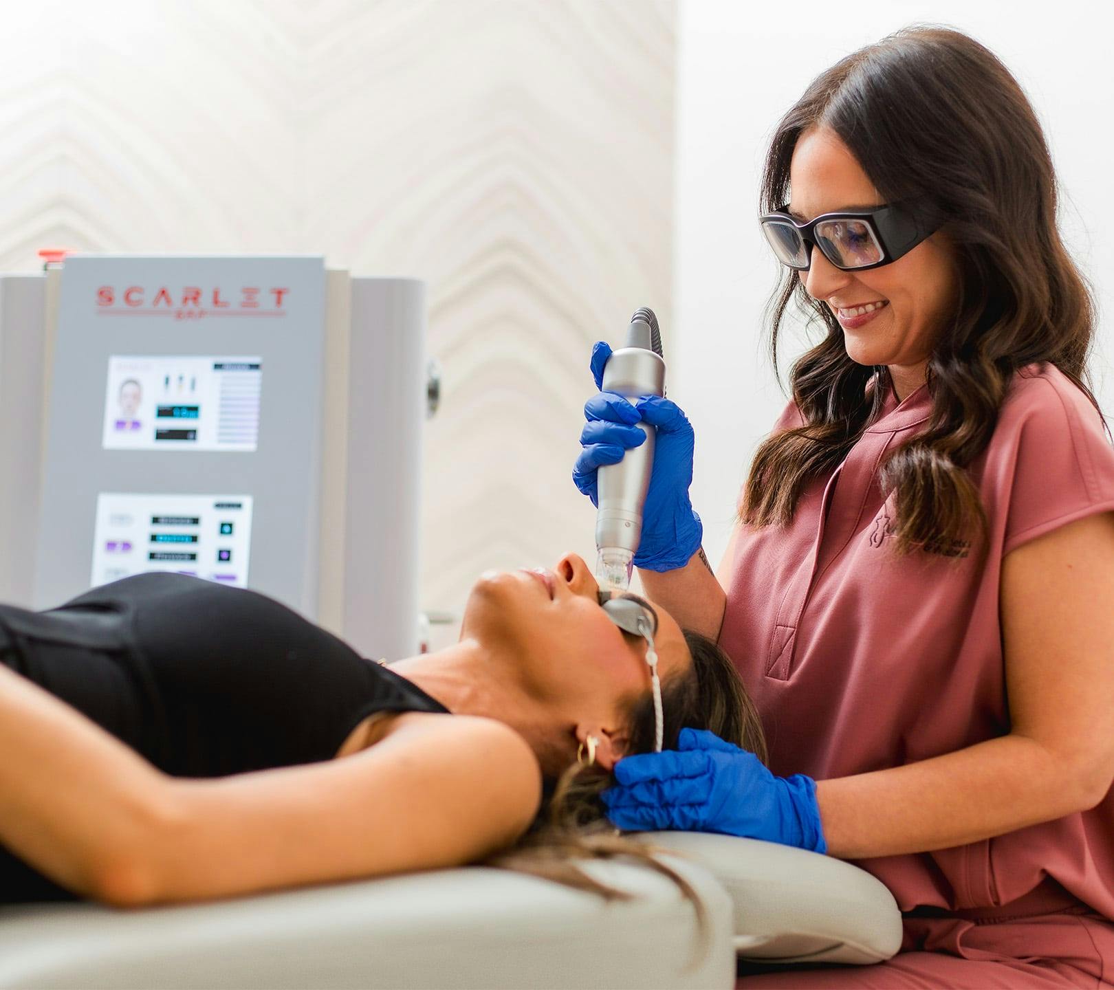 nurse smiling as she does facial treatment on patient
