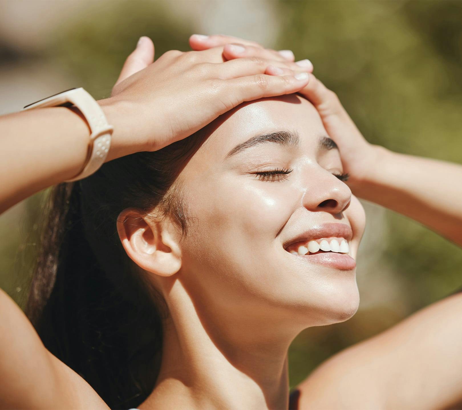 woman smiling with hands on her forehead while facing the sun light