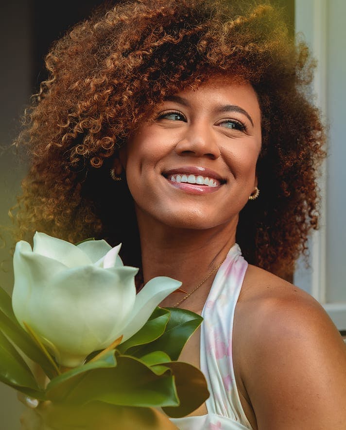 Smiling woman holding a white flower