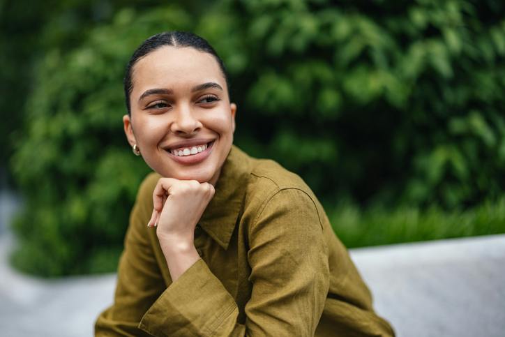 woman with smile and hand on chin and hair tied back