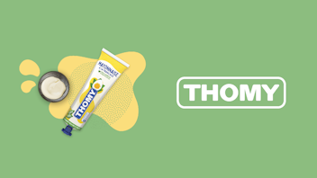 A tube of Thomy mayonnaise with an open cap and mayonnaise dollop is shown on a green background next to the Thomy logo.