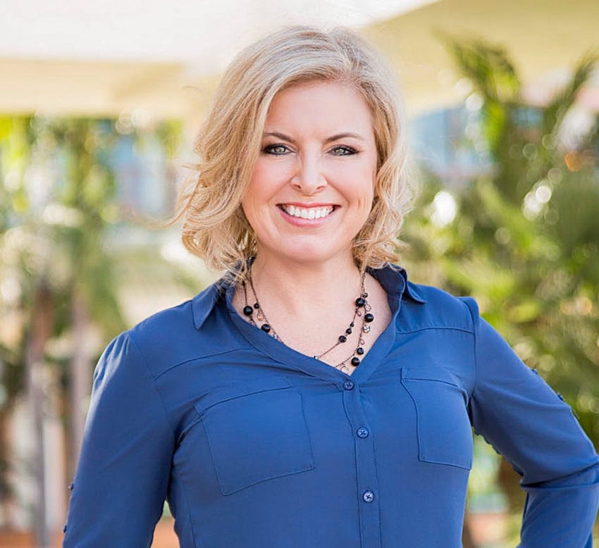 woman with short blonde hair smiling in blue top