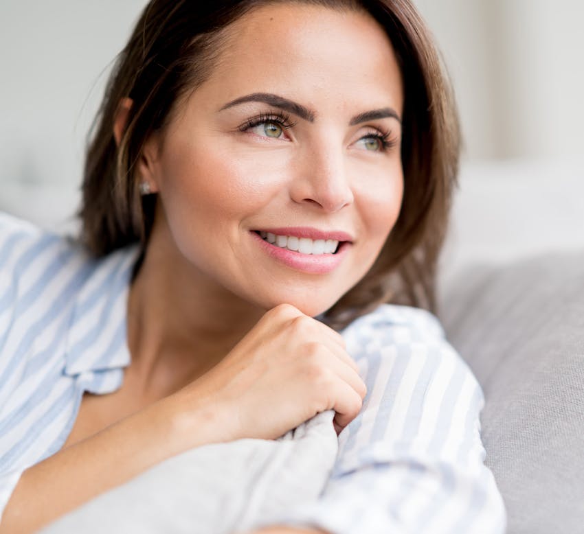 woman smiling while hugging a pillow