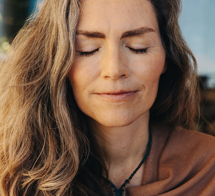 woman with her eyes closed wearing brown shirt