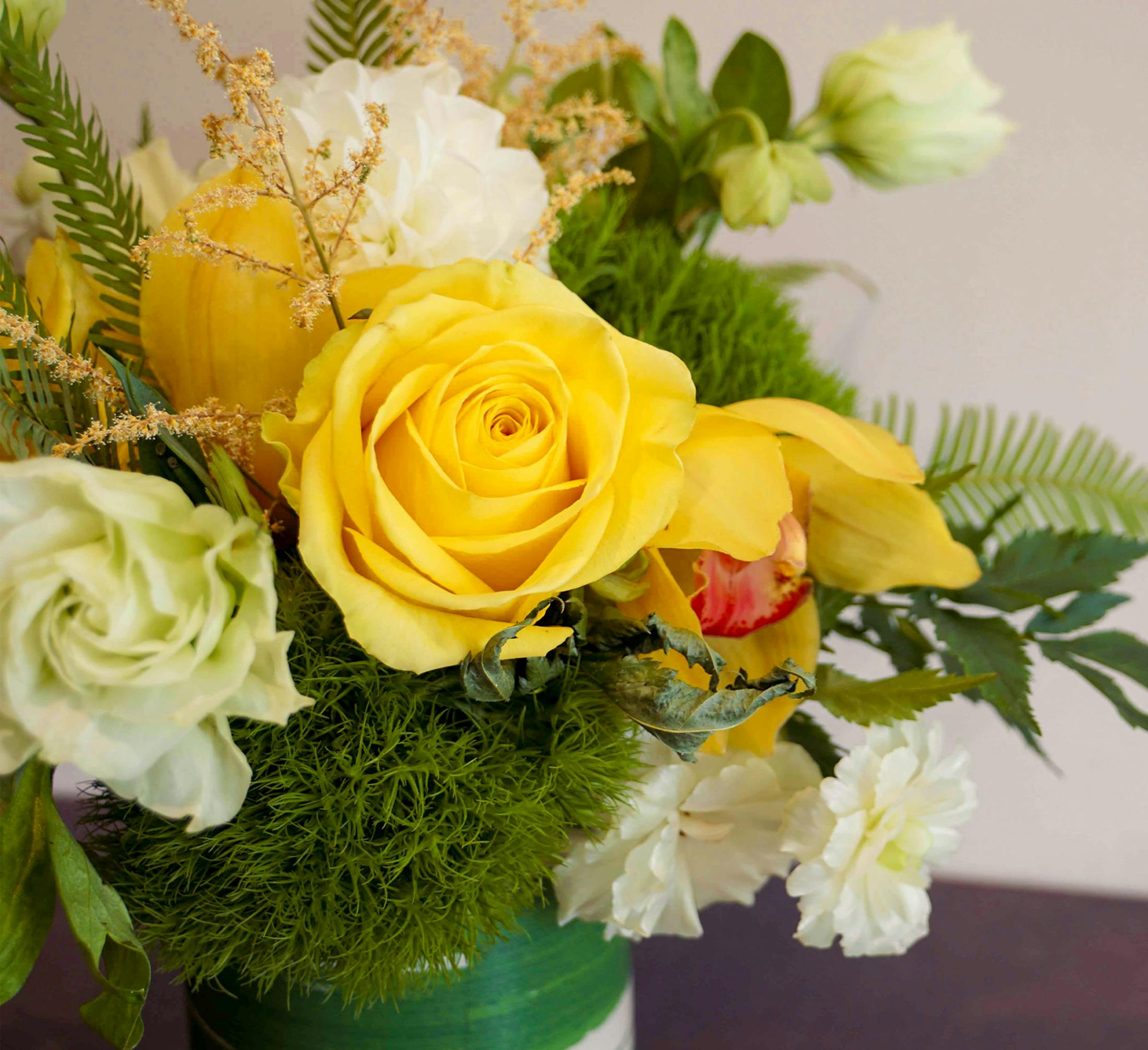 a vase of different types of yellow flowers