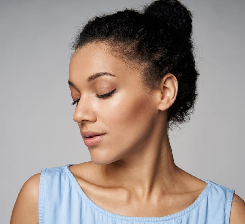 woman with her hair tied up in a bun while her face is facing to the left