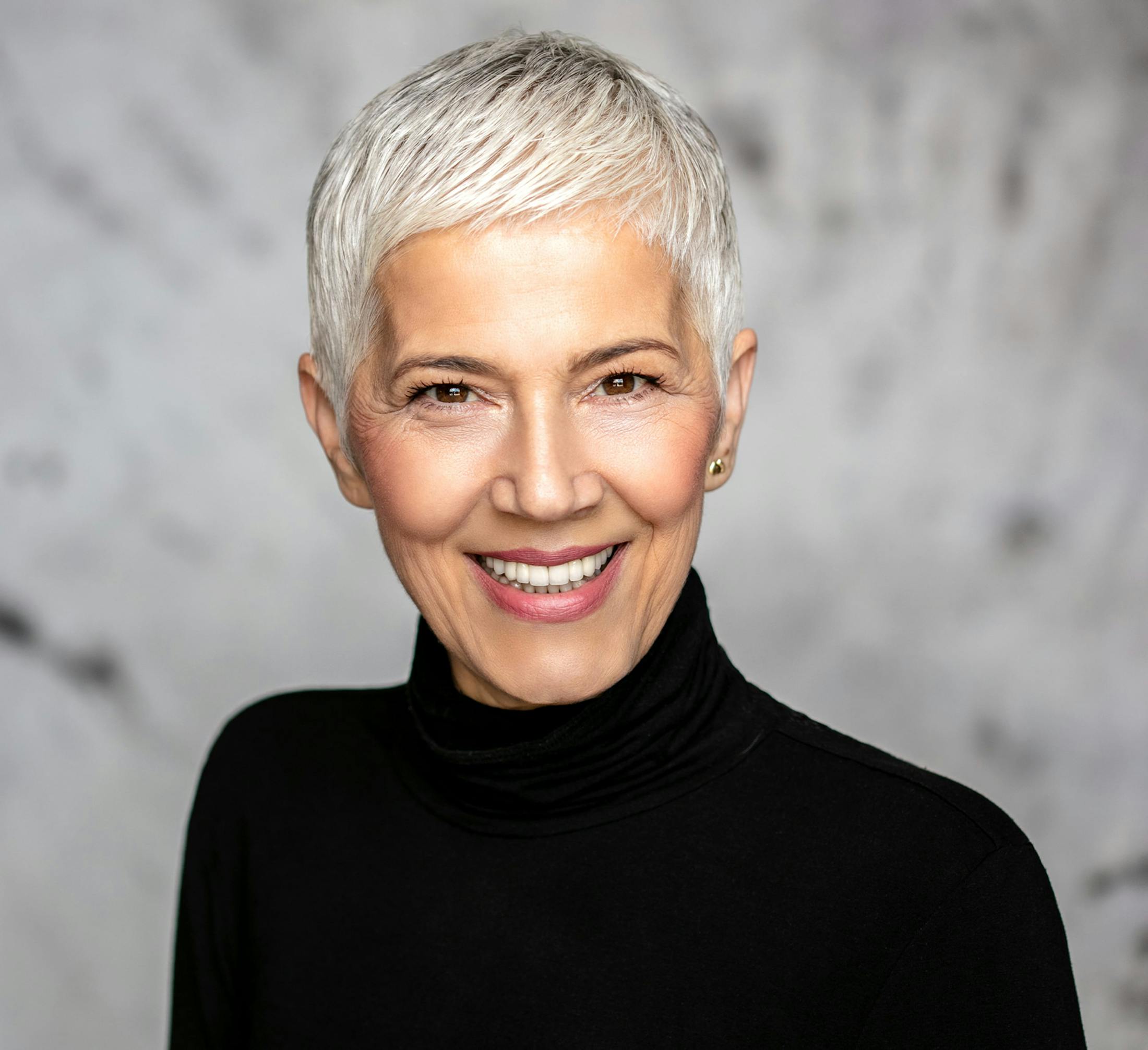 woman with short gray hair in black turtleneck smiling