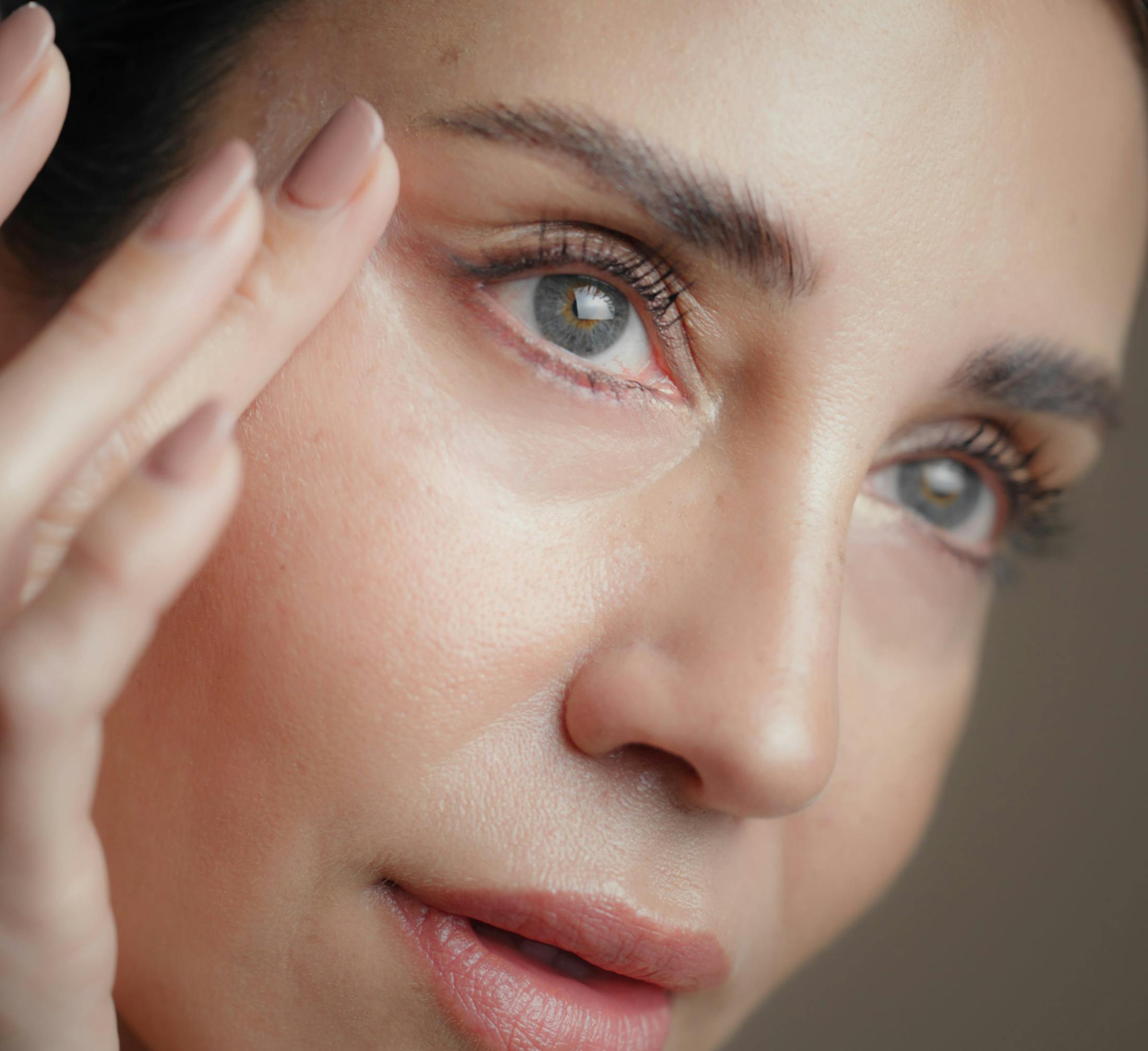 close up of woman's face while she touches the skin by her eyes