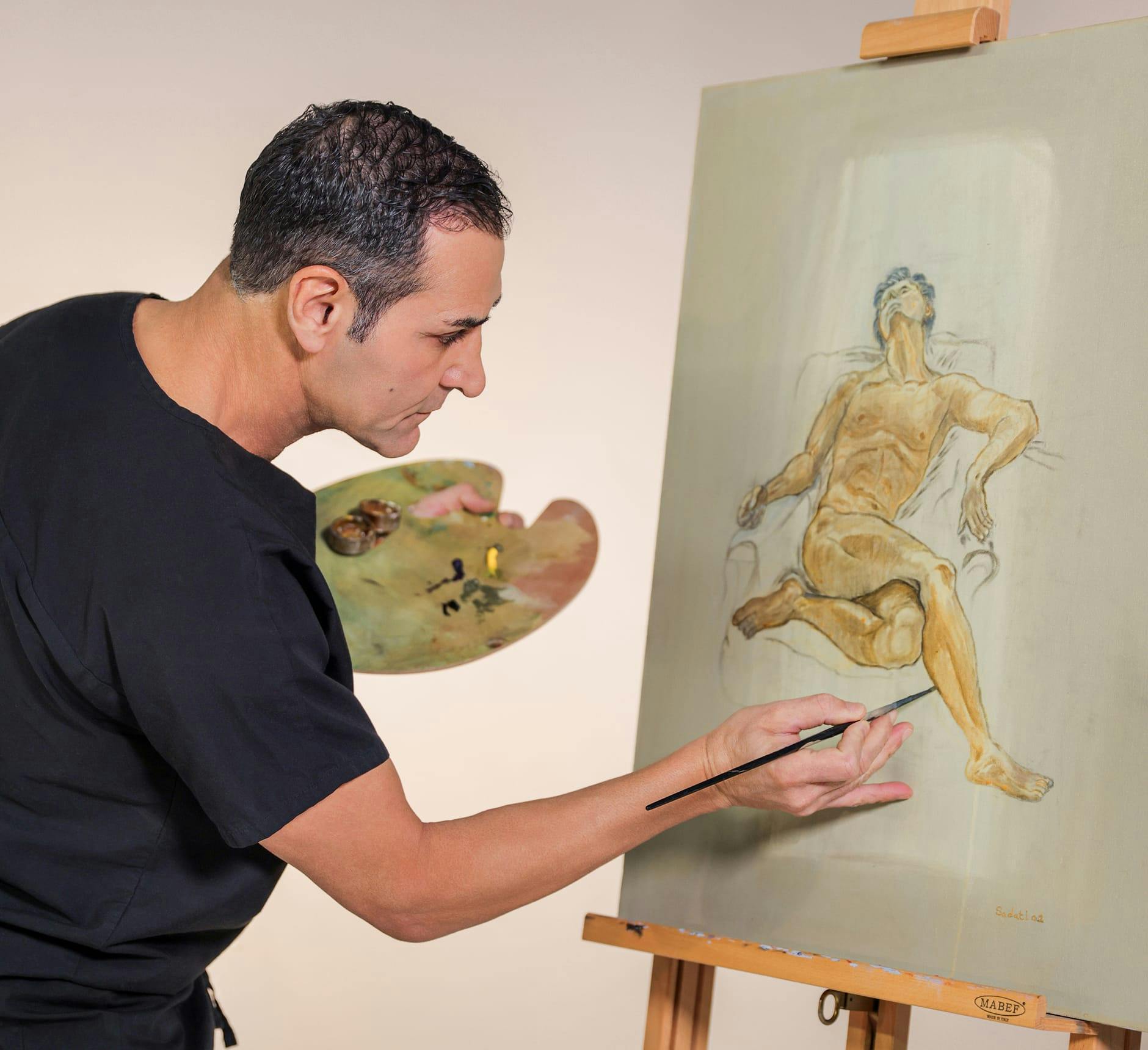 Dr. Kevin Sadati painting a portrait of a man laying down on an aisle