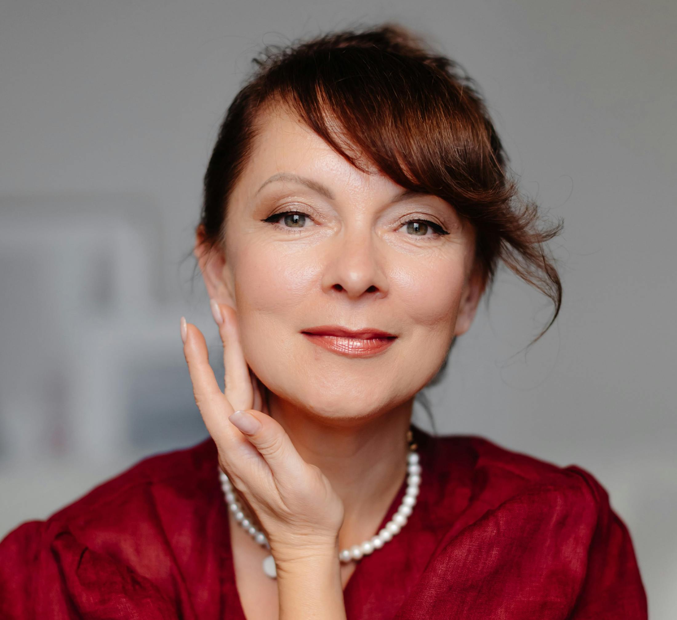 woman looking forward with side bangs while touching her jawline