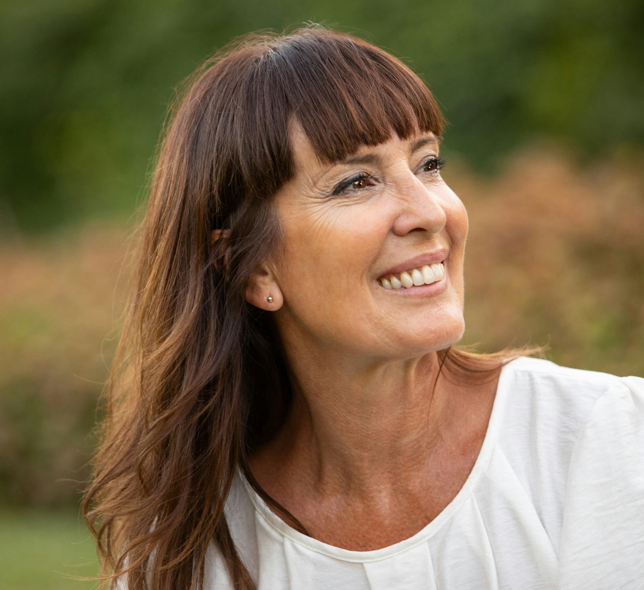 woman with dark hair and bangs smiling outside