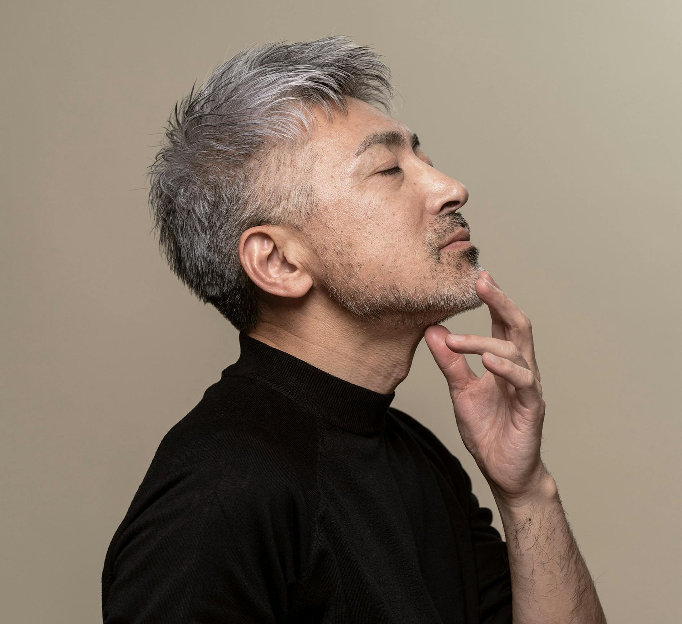 side profile of man touching his chin with head tilted back and eyes closed