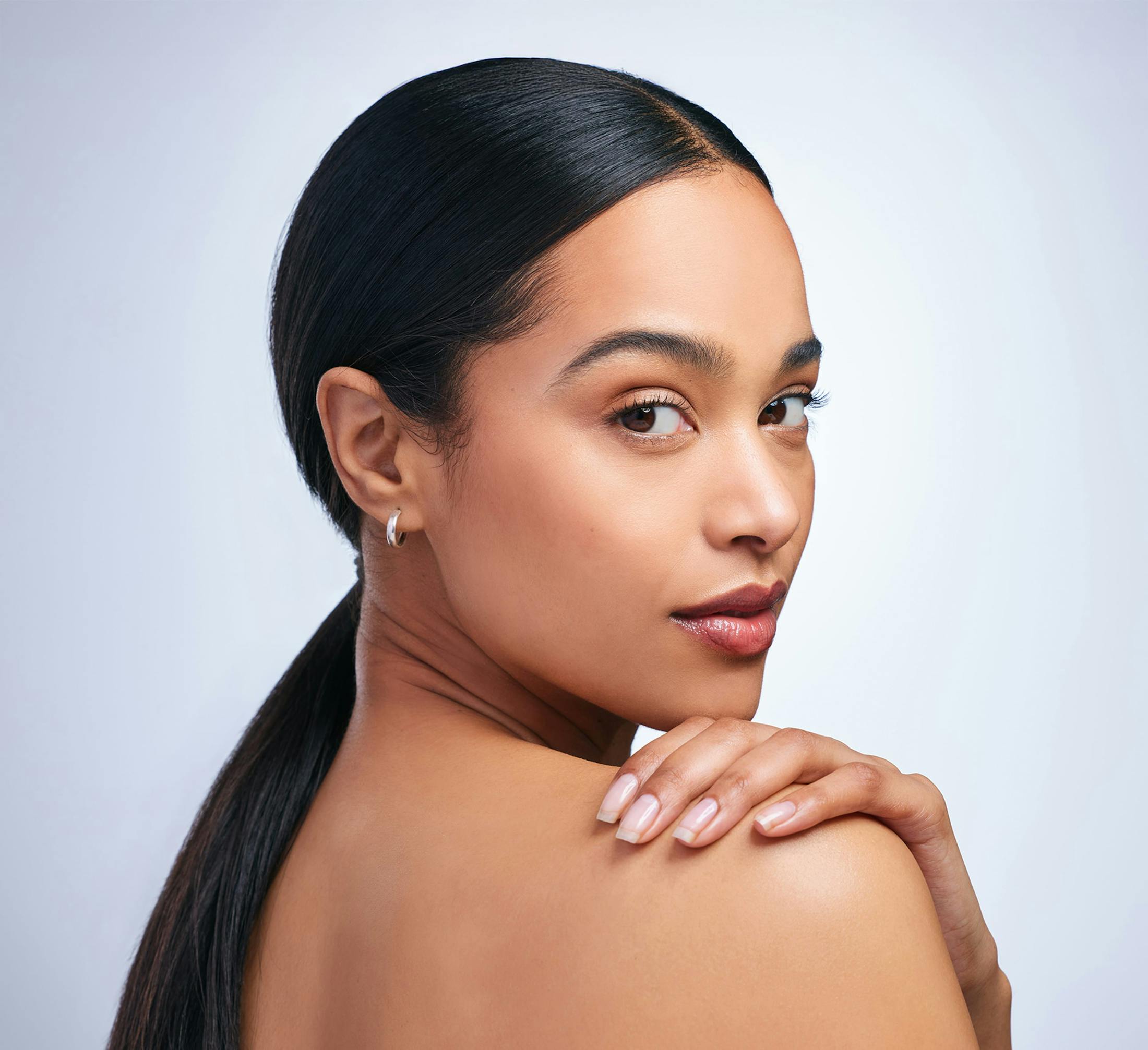 woman looking over her shoulder, with opposite hand on shoulder.