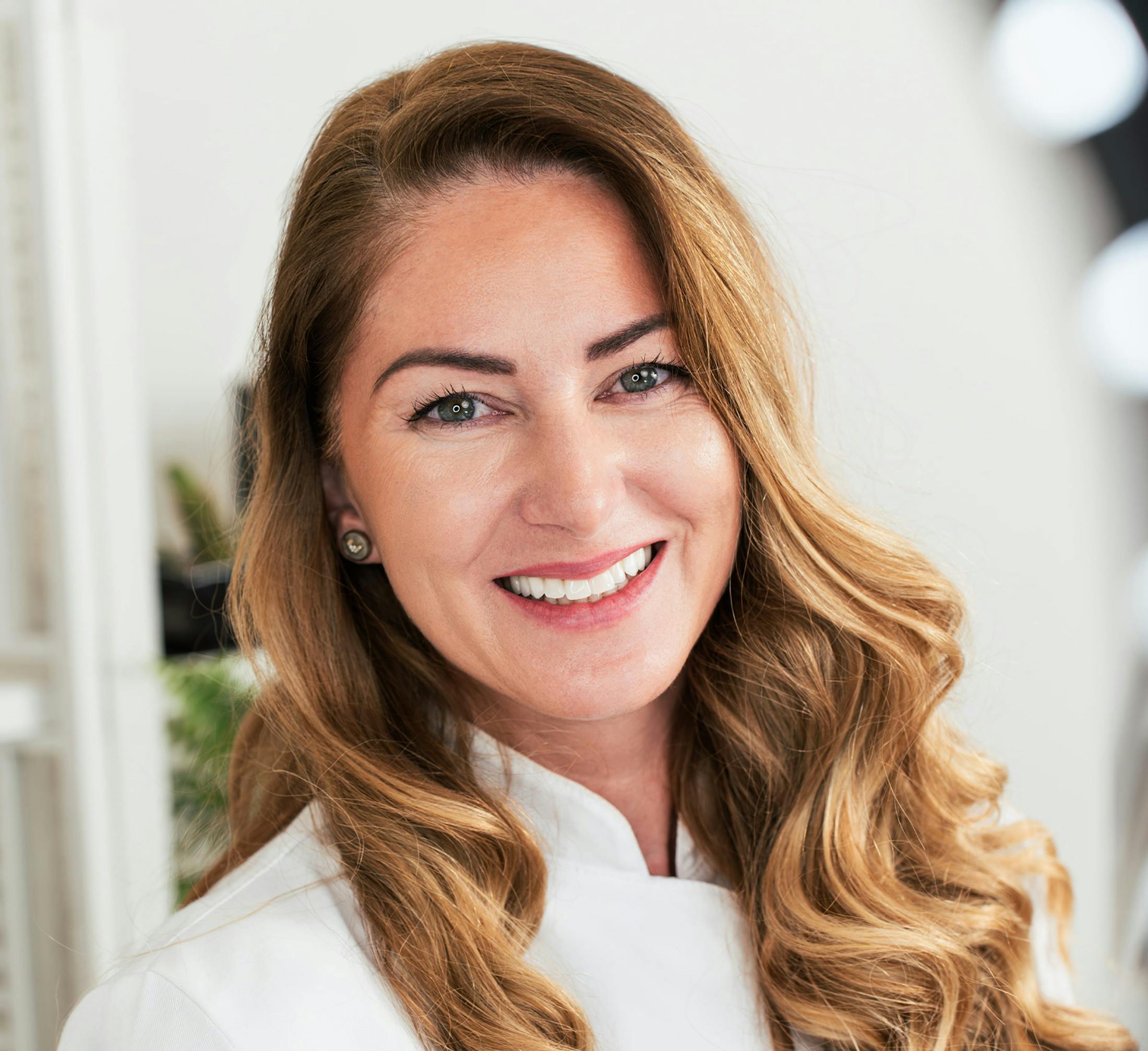 woman with curled long blonde hair smiling looking forward