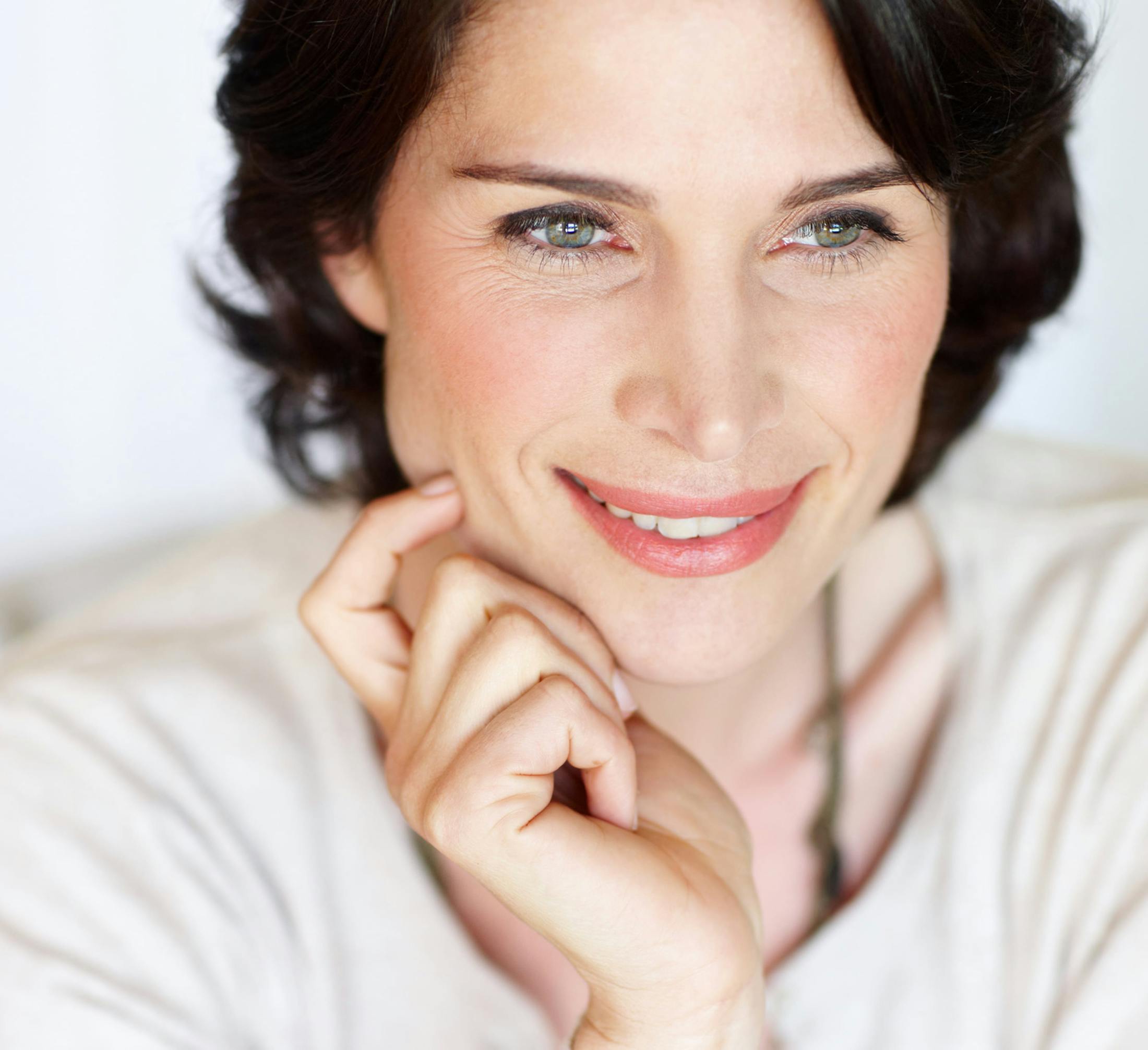 woman with dark short hand and hand placed on her jaw