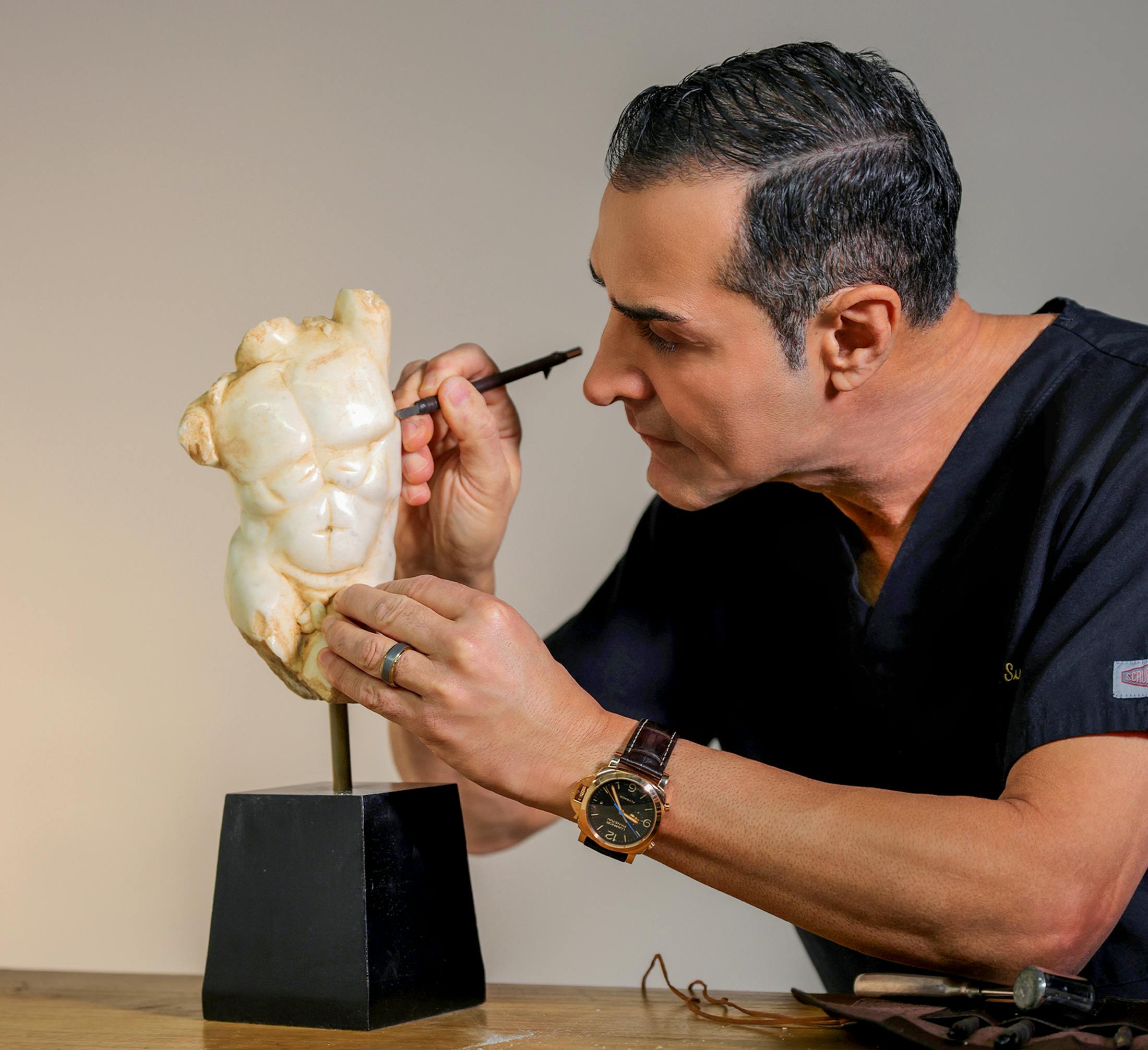 Dr. Kevin Sadati carving a sculpture of a man with fine tip tool