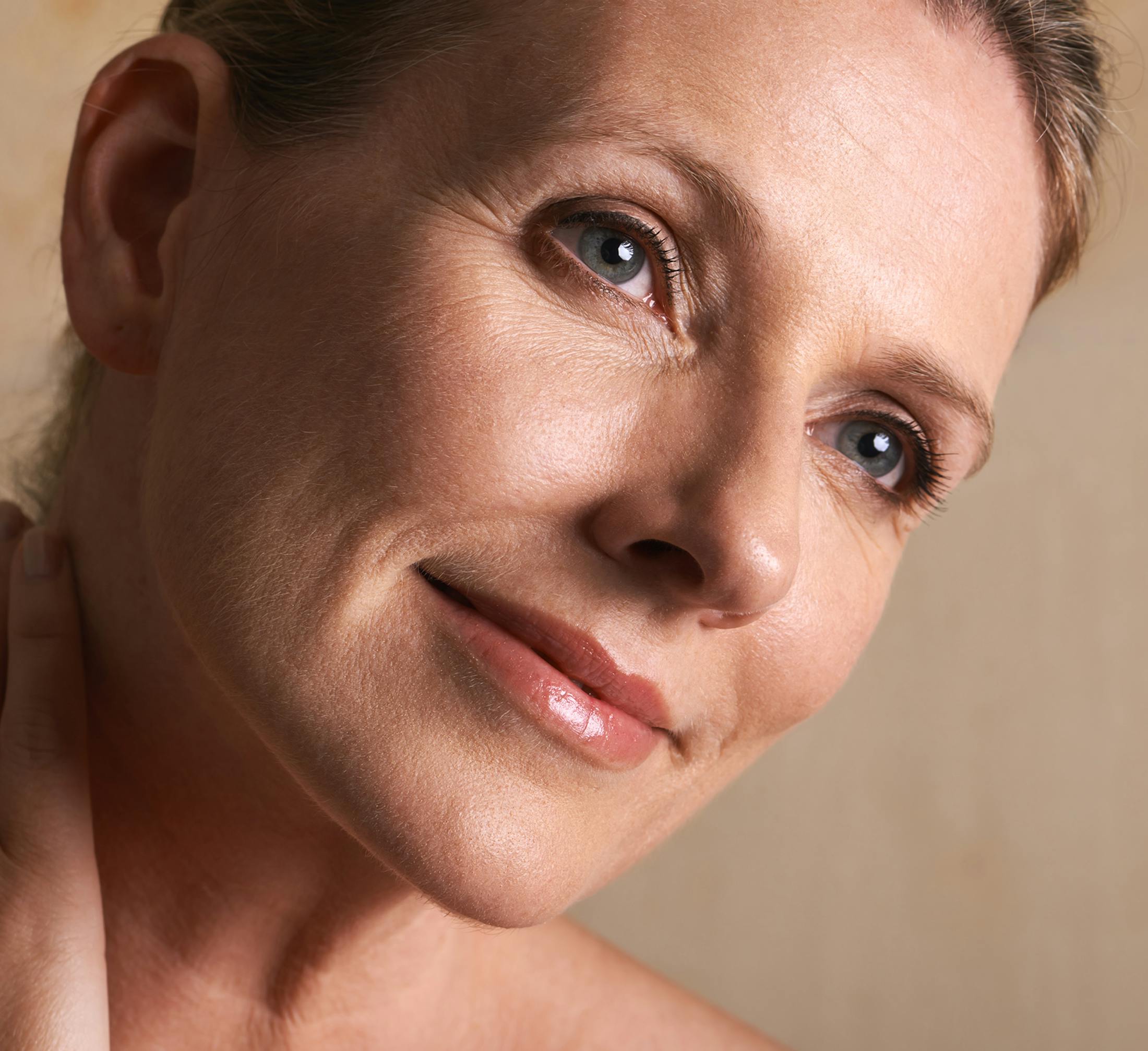 close up of woman's face, head tilted with hand on neck