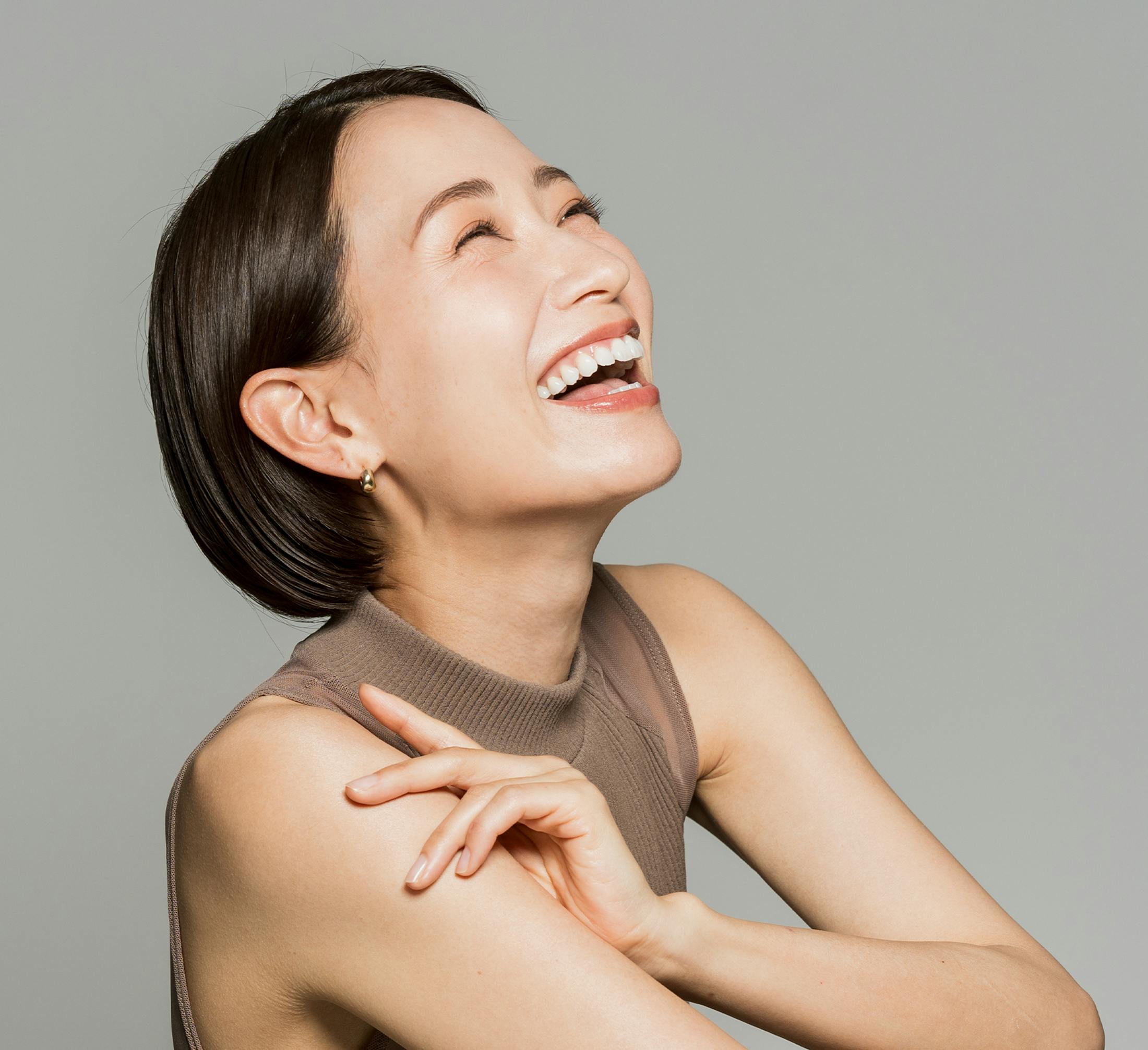 woman with short bob laughing with eyes closed, head tilted up
