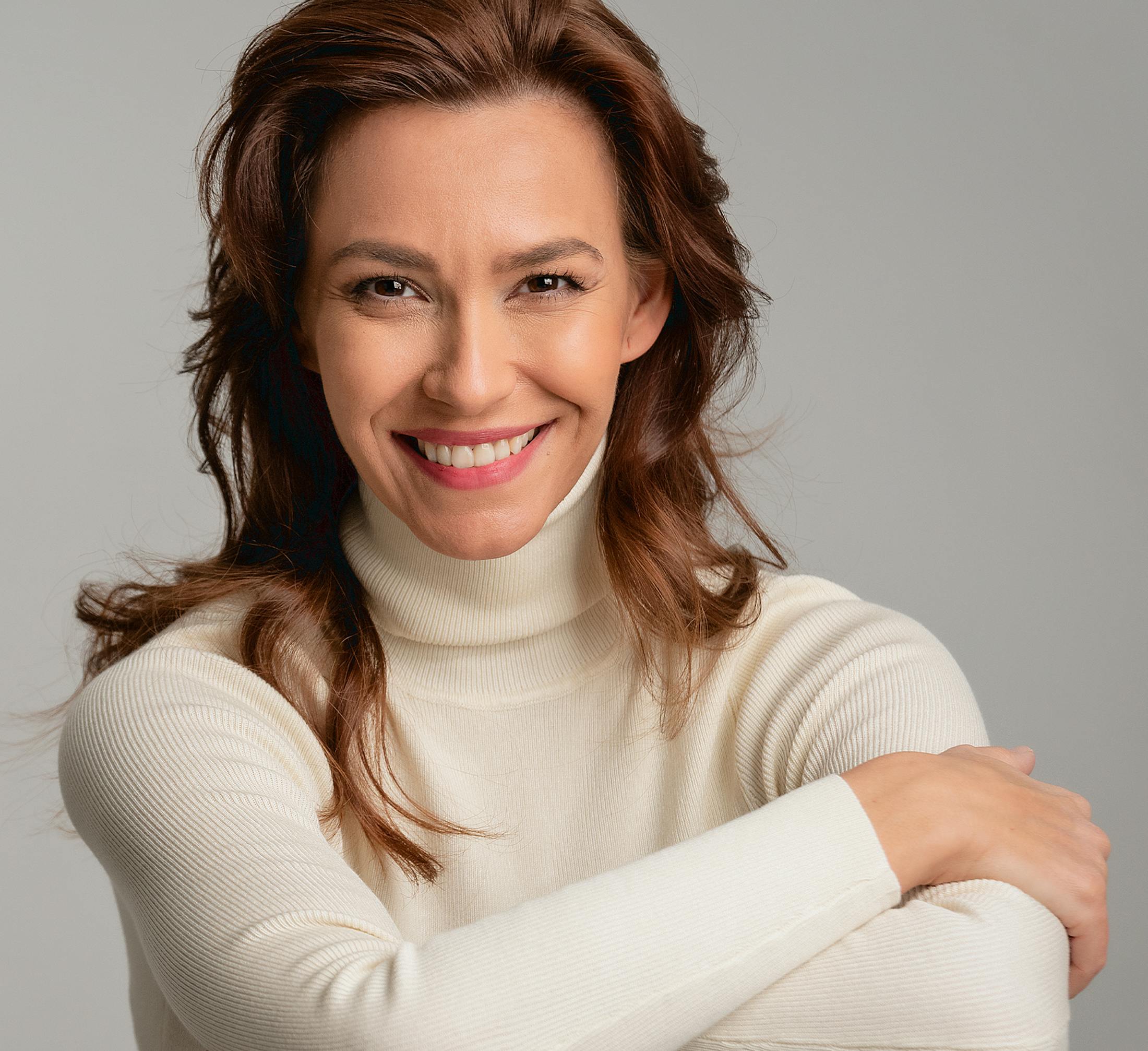 woman in while turtle neck smiling looking forward