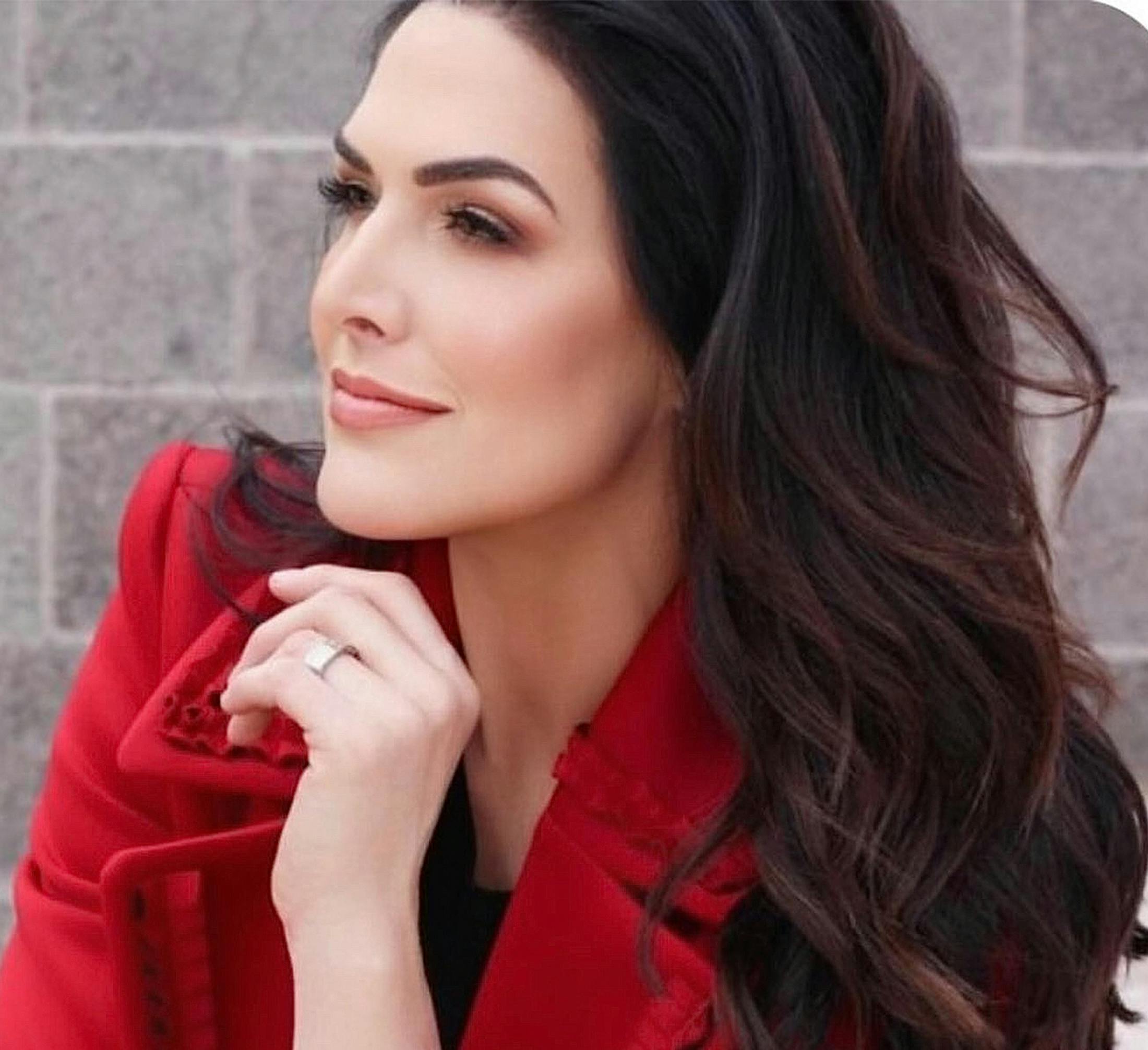 woman with long dark hair in red blazer looking forward