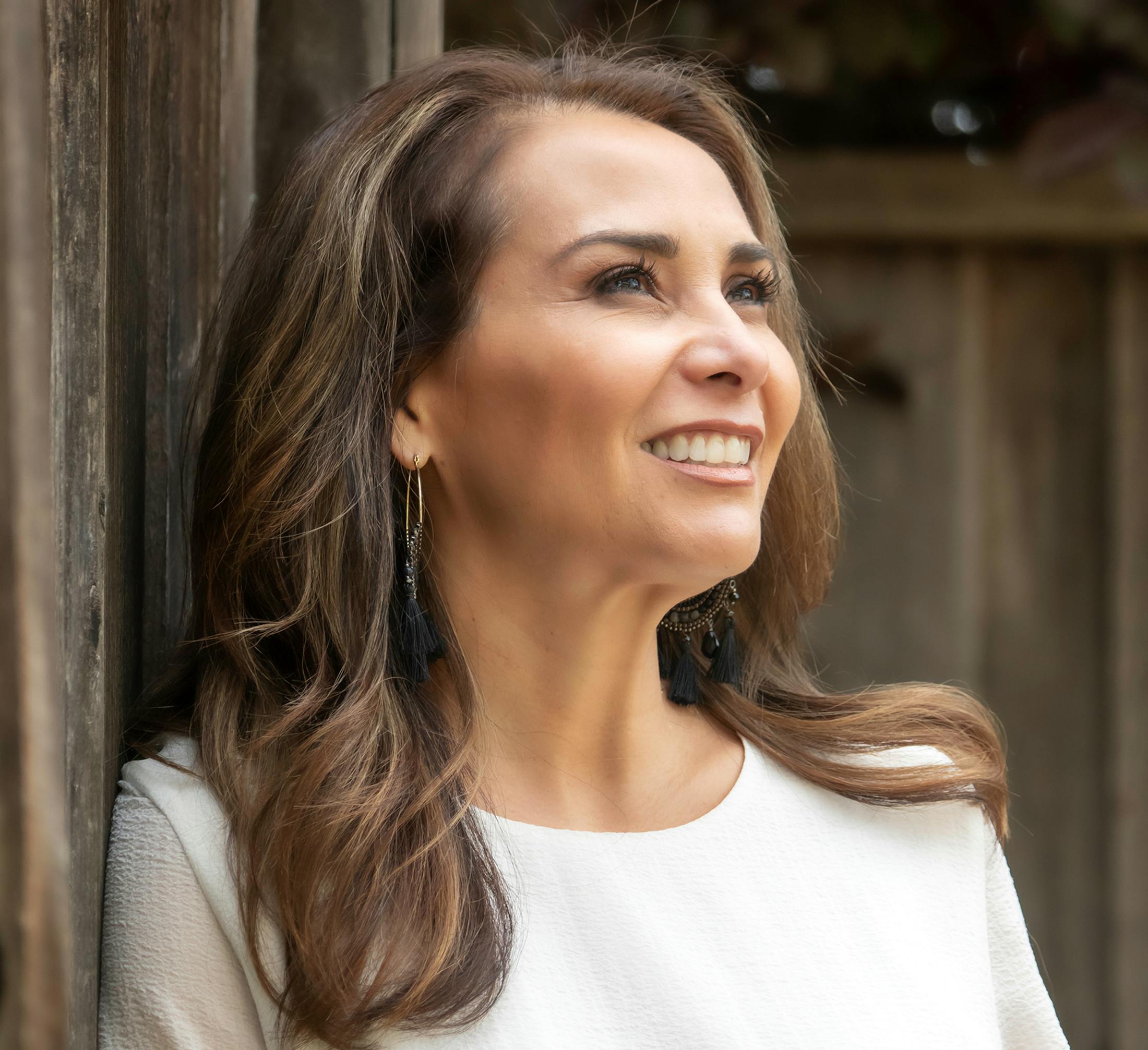 woman smiling in white shirt against wooden structure